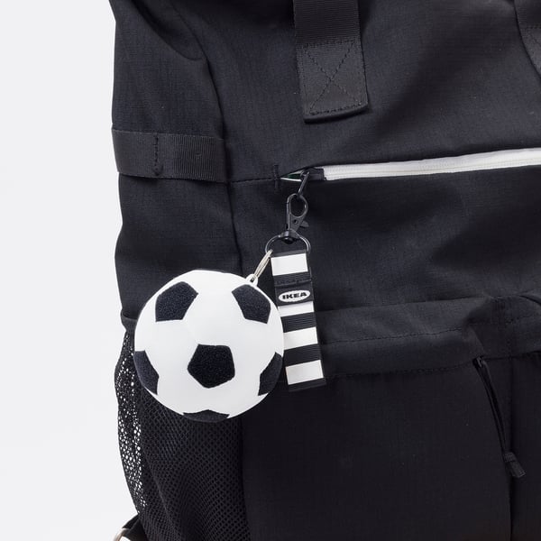 Black backpack with side football ball charm, ce marked, IKEA tag visible.