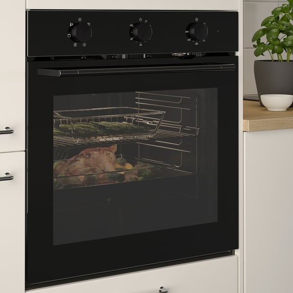Black built-in oven with glass door, cooking large meat dish and vegetables, featuring even heat distribution and multiple cooking racks.