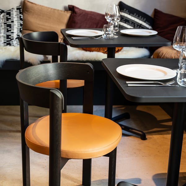 Modern café setup with square tables and chairs, elegantly arranged for dining or meetings.