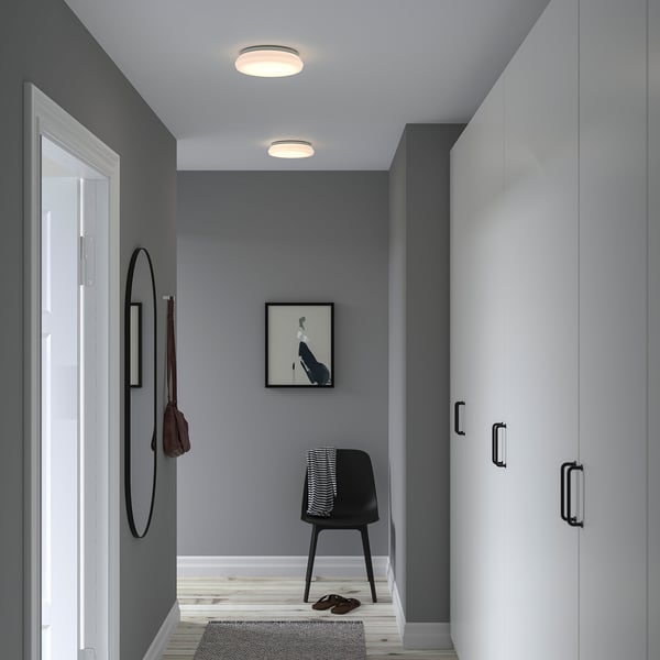 Hallway with grey walls, white cabinet, STOFTMOLN lamp, mirror, chair with blanket, picture.