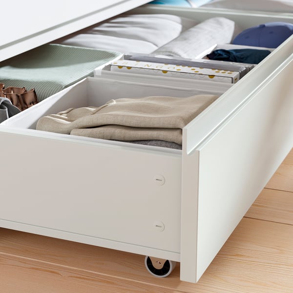 Open underbed storage drawers with neatly folded clothes and boxes.