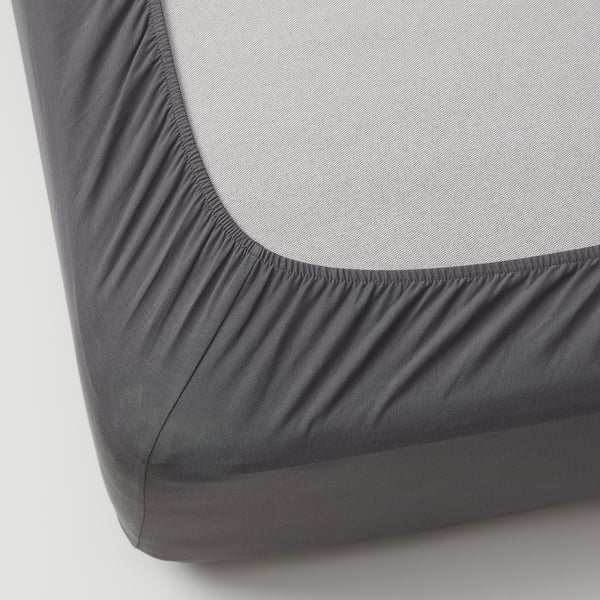 Grey fitted sheet with elastic edges over a white mattress, showcasing its stretchy fit and smooth fabric.