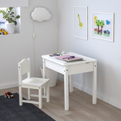 Kids white wooden desk and chair set. Compact, with a lift-up lid for storage. Bright, colourful art prints on wall. Ideal for small spaces.