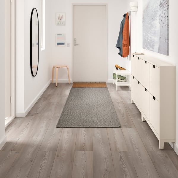 Modern hall with TIPHEDE gray rug, white storage, wooden stool, and wall art.