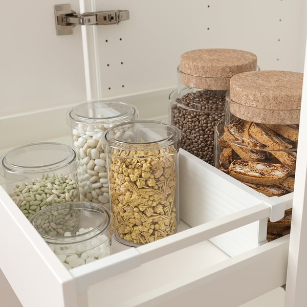 Kitchen drawer with adjustable organisers holding glass food containers, corked jars, and a divider for tidy storage.