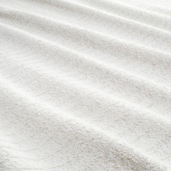 Close-up of VÅGSJÖN towel, showing soft, textured terry cloth with a striped pattern. 100% cotton, plush and absorbent.