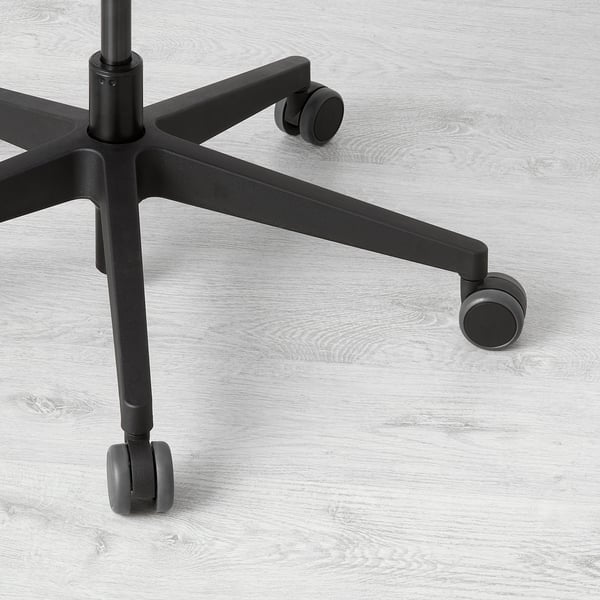 Black office chair base with five castors on wooden floor. Sturdy, adjustable design for stability and easy movement.