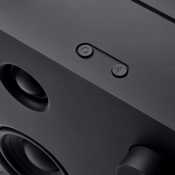 Close-up of a sleek black VAPPEBY bluetooth speaker featuring a round power button and a bluetooth pairing button, set against a dark background.