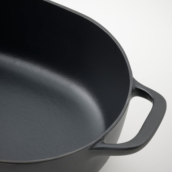 Close-up of black enamelled cast iron pan handle, smooth and sturdy, highlighting durable quality.