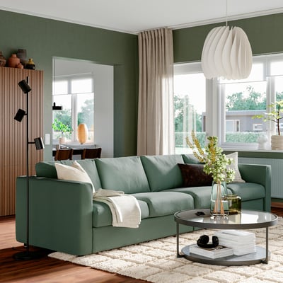 Meadow green VIMLE sofa, plush with cushions, positioned centrally, inviting relaxation.