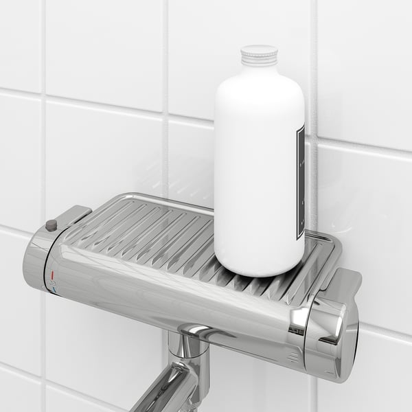 A chrome bathroom shower mixer a built-in shelf holding a white bottle, perfect for storing tall shampoo bottles.