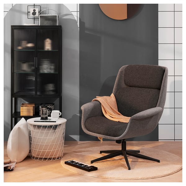 Elegant minimalistiskt rum med ÄLEBY grå snurrfåtölj med justerbar lutning, modernt runt sidobord och vitrinskåp.