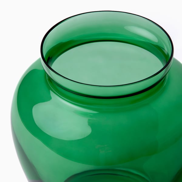 Vas i grönt glas, handgjord med släta, rundade kanter. Visar små variationer, bevis på skickligt hantverk.