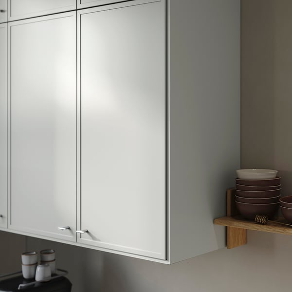 Minimalistiskt köksskåp med tunn ram; ljusgrå finish, monterat gångjärn synligt.