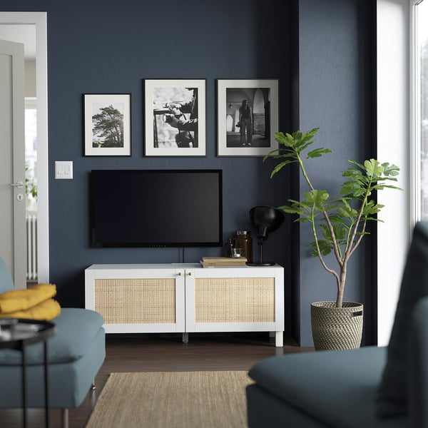 Modernt vardagsrum med tv-bänken BESTÅ, konst, blå stol, gula dynor, växt, jutematta.