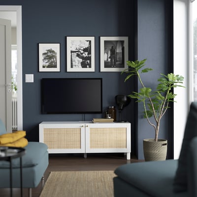 Modernt vardagsrum med tv-bänken BESTÅ, konst, blå stol, gula dynor, växt, jutematta.
