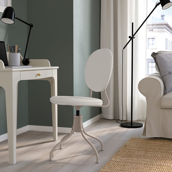 Modernt hemmakontor med vit stol BJÖRKBERGET. Snygg design, vadderad, justerbar. Skrivbord, lampa och soffa i närheten. Stort fönster med utsikt.