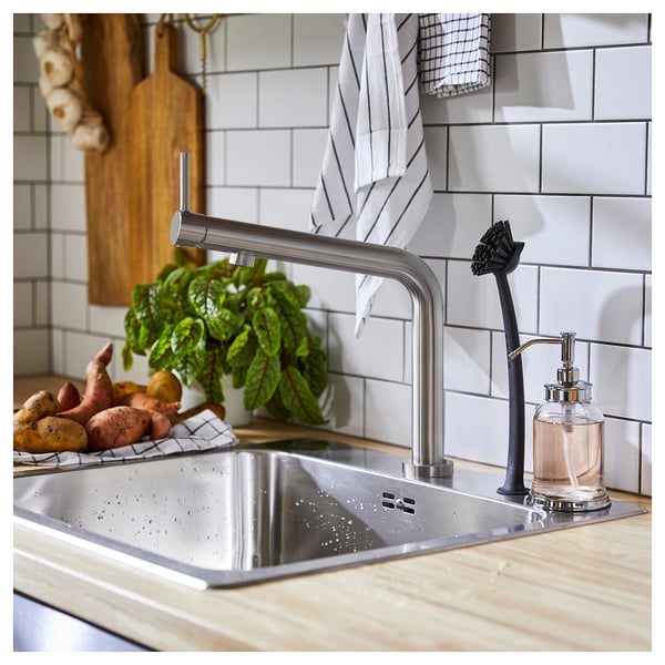 Modern köksblandare med finish i rostfritt stål, elegant design och handtag på toppen. Grönsaks- och tvålpump i närheten.