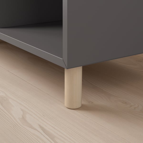 Grå förvaringsmöbel med träben på ett ljust trägolv. Kvalitetsmaterial och minimalistisk design.