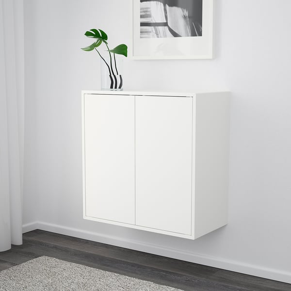 Vitt vägghängt förvaringsskåp med två dörrar och en krukväxt på toppen.
