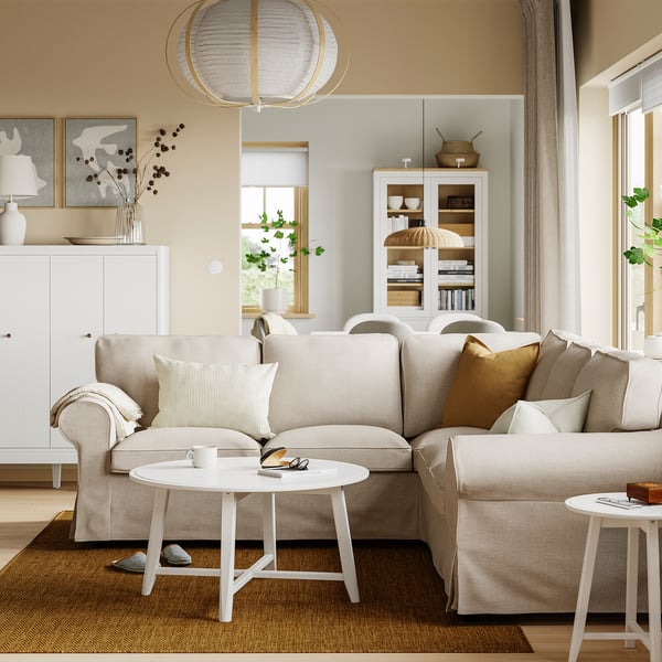 Rymligt vardagsrum med stor EKTORP-soffa, bekväma kuddar, omgiven av ett sidobord, matta och skåp i en harmonisk, neutral inredning.