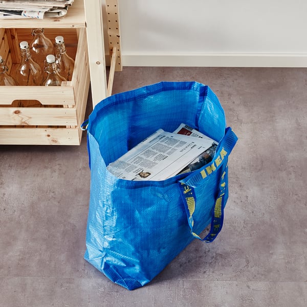 Blå ikea FRAKTA-påse på golvet med papper.
