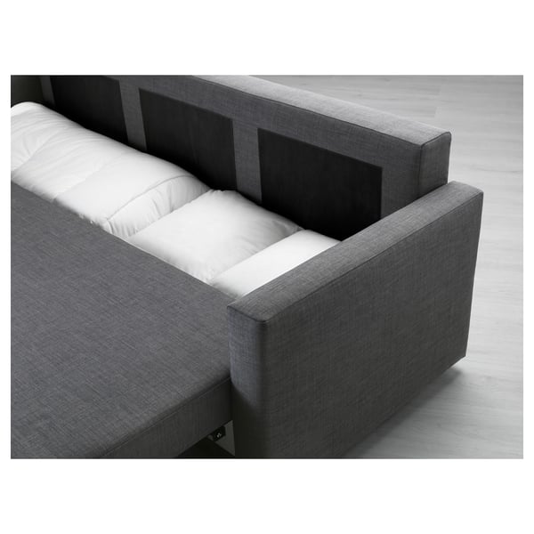 Modern grå bäddsoffa med vita kuddar, med inbyggd förvaring för sängkläder och bäddbara sittplatser.