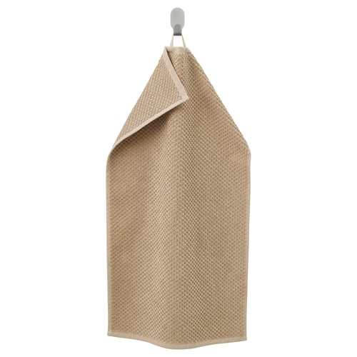 Beige GULVIAL handduk hänger snyggt på kroken, tillverkad av mjuk, absorberande 100% bomull i en fluffig struktur.