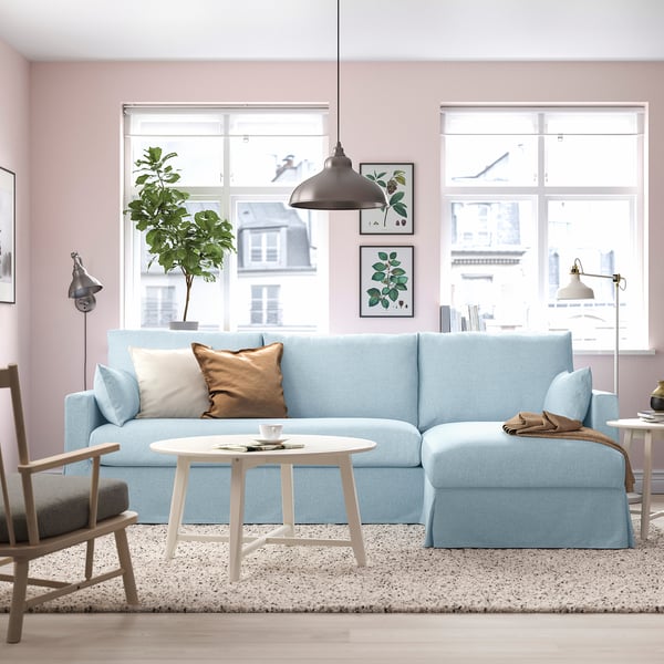 Ljusblå sektionssoffa, soffbord, matta, fönster, inramad konst