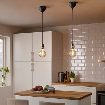 Modernt kök med 2 JÄLLBY pendellampor över en ö i trä, prydda med frukter och blommor.