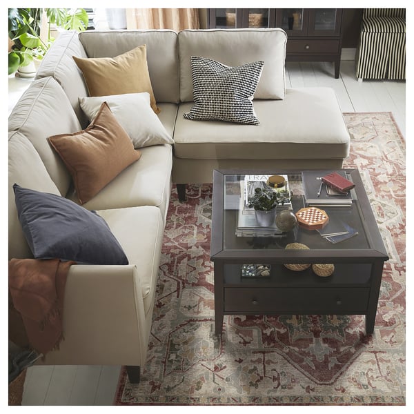 Modern vardagsrum med neutral soffa och färgglada kuddar på en mönstrad matta.
