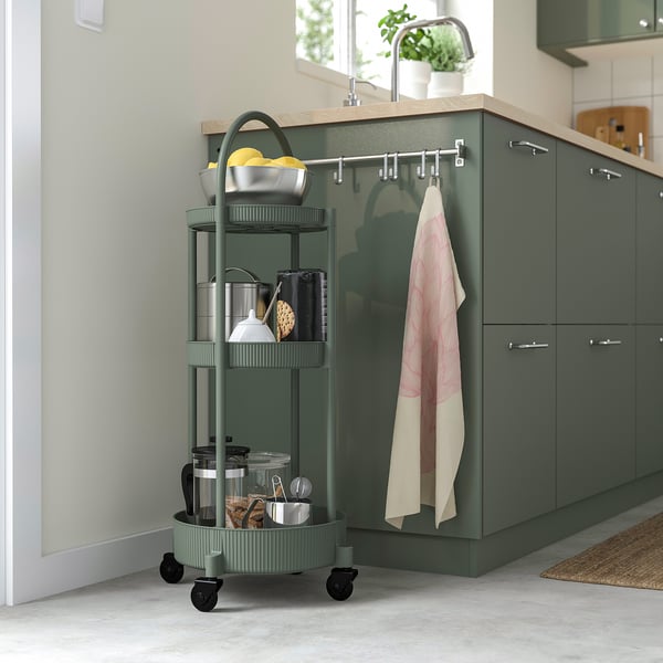 Modern grågrön JUTTERSBO-vagn med 3 hyllor rymmer köksnödvändigheter, passar snyggt bredvid skåp.