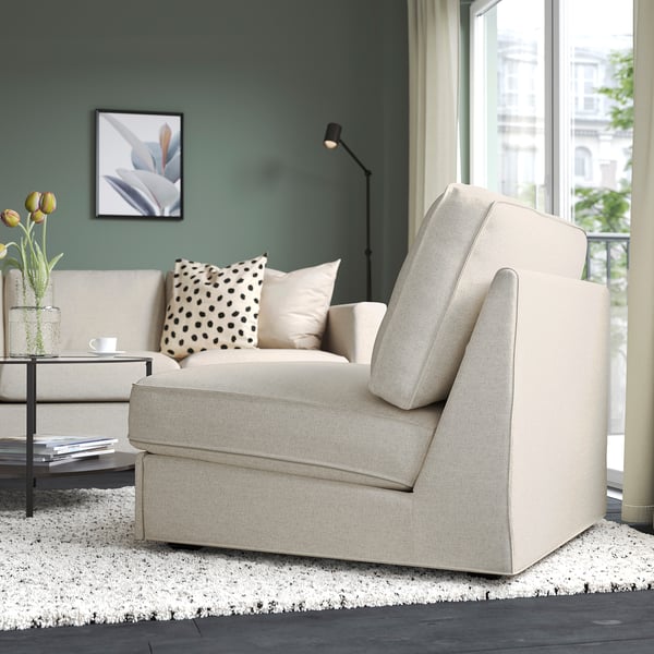 Modernt vardagsrum med beige bäddsoffa, prickig kudde, rislampa, glasbord, blommor och utsikt över staden.