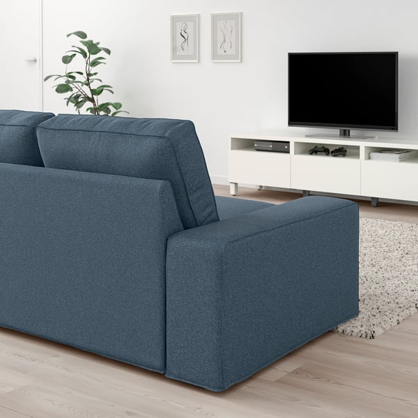 Modernt vardagsrum med stor blå KIVIK-soffa, elegant tv-bänk och elegant inredning.