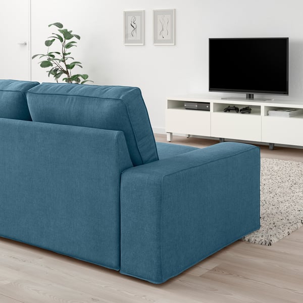 Modernt vardagsrum med KIVIK blå soffa, platt-tv och växt.