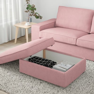 Föreställ dig en rosa KIVIK fotpall med öppet förvaringsfack som avslöjar tidningar och en filt.