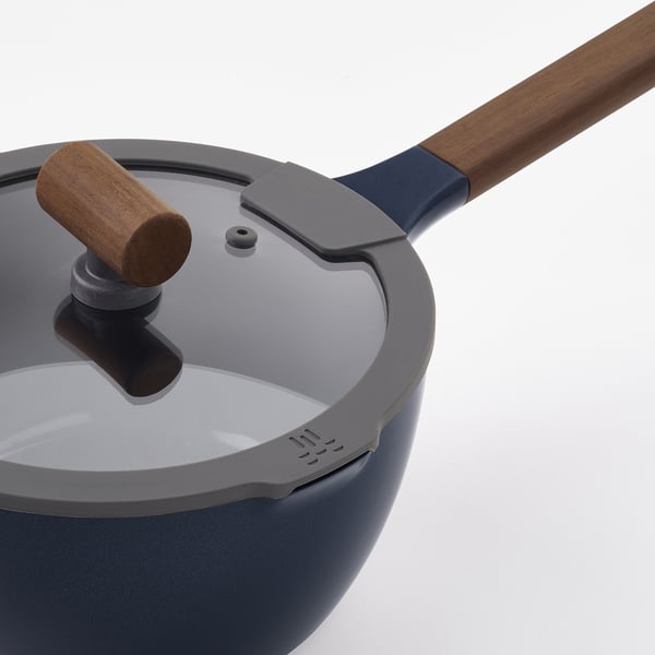 Närbild av modern kastrull med trähandtag, med non-stick inredning, säkert lock och snygg design.