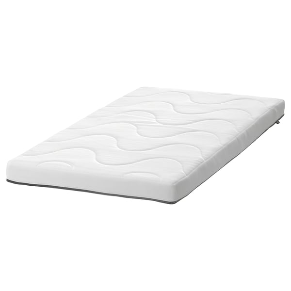 En vit KRUMMELUR spjälsängsmadrass från ikea, rektangulär med vågiga och släta sidor, och ett tvättbart överdrag med dragkedja.