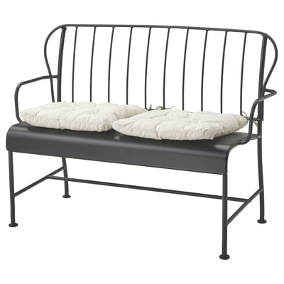 Modern utomhusbänk i svart metall med vita kuddar, elegant design med böjd rygg och armstöd.