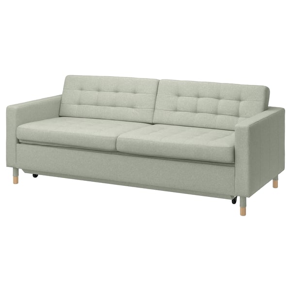 Ljusgrön soffa med träben, fyrkantiga kuddar och modern design.