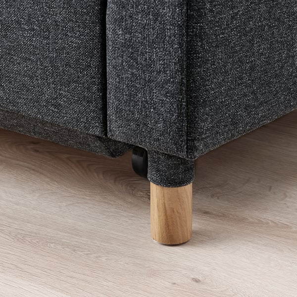 Närbild på en modern, stoppad bäddsoffa med ben och golv i trä. Kvalitetsträ, snyggt och hållbart.
