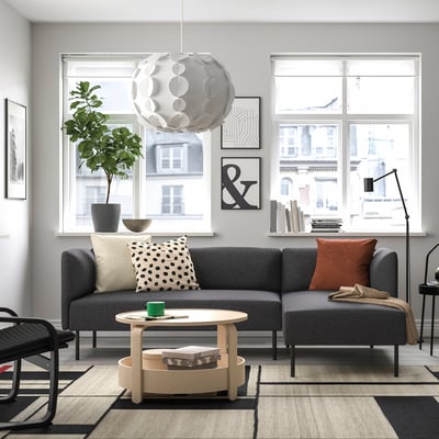 Modernt vardagsrum: grå modulsoffa LILLEHEM med detaljer i trä, elegant taklampa, mönstrad matta och stora fönster med utsikt över staden.