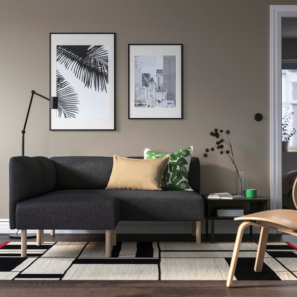 Modernt vardagsrum med grå soffa LILLEHEM, kuddar, konst, lampa och mönstrad matta.