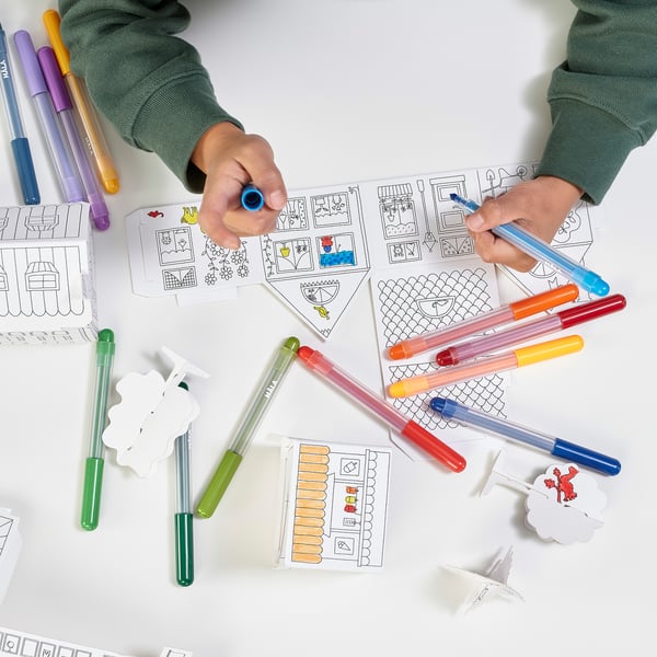 I en person skapar en stad med hjälp av MÅLA kartongmallar och markipennor, vilket visar på kreativitet och finmotorik.