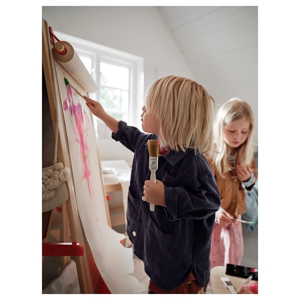 Två barn står och målar på ett MÅLA staffli med whiteboards i ett ljust rum. Den ena håller i en pensel, den andra en penna.