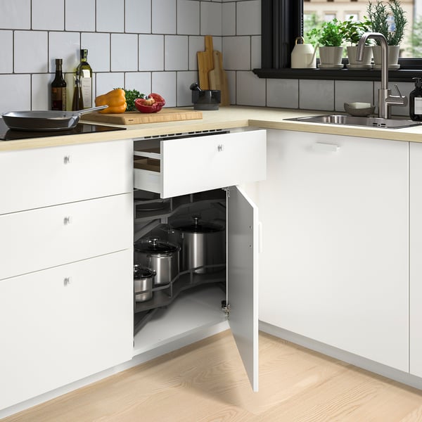 Modernt vitt köksskåp med inbyggda hörnhyllor som håller kastruller, vilket sparar utrymme effektivt.