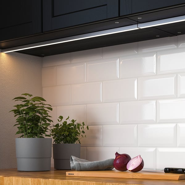 Kök med LED-lampor under skåpet som lyser upp bänkskivan. Växter och lök på träbänken.
