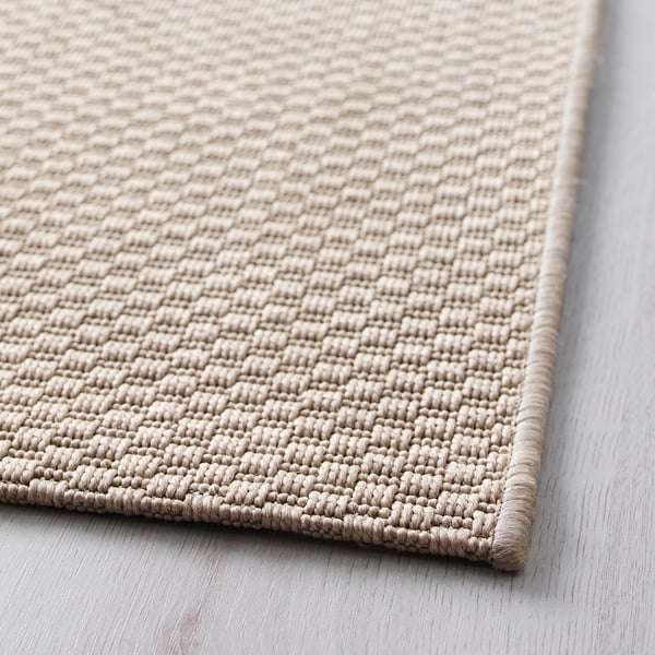 Mjuk, beige vävd matta på trägolv som visar upp kvalitet, struktur och design.