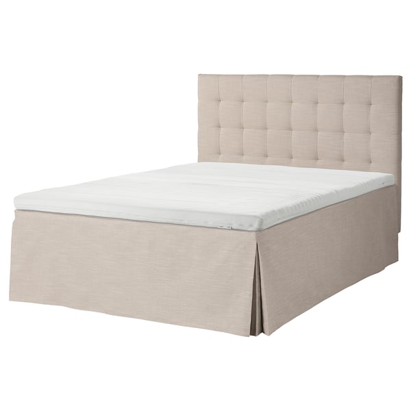 En beige säng från STERHAMN med en tuftad sänggavel och en kjolbotten. Sängen är rektangulär och designad för komfort.
