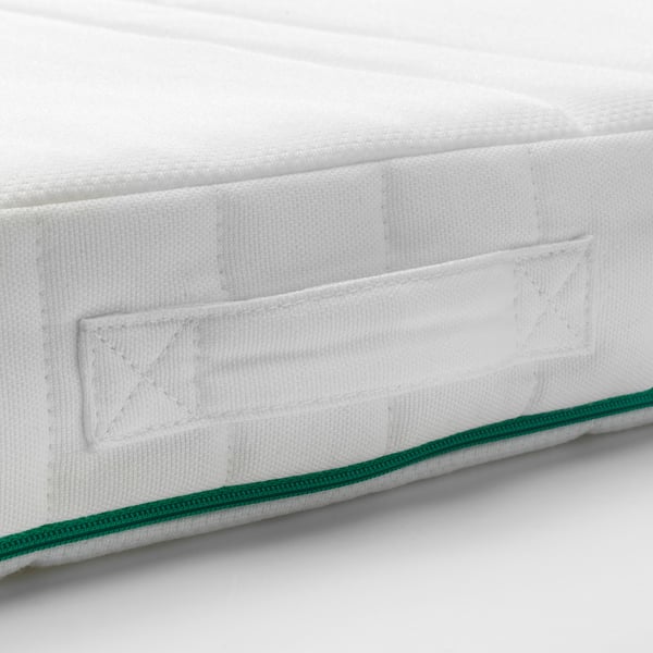 Närbild av en vit madrasshörna med grön kant, som visar upp quiltad design för komfort.